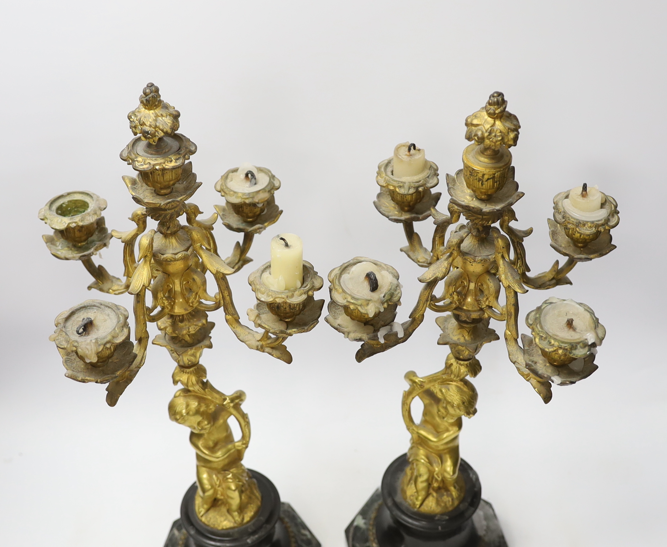 A pair of late 19th century French ormolu cherubic four branch candelabra on marble bases, 47cm